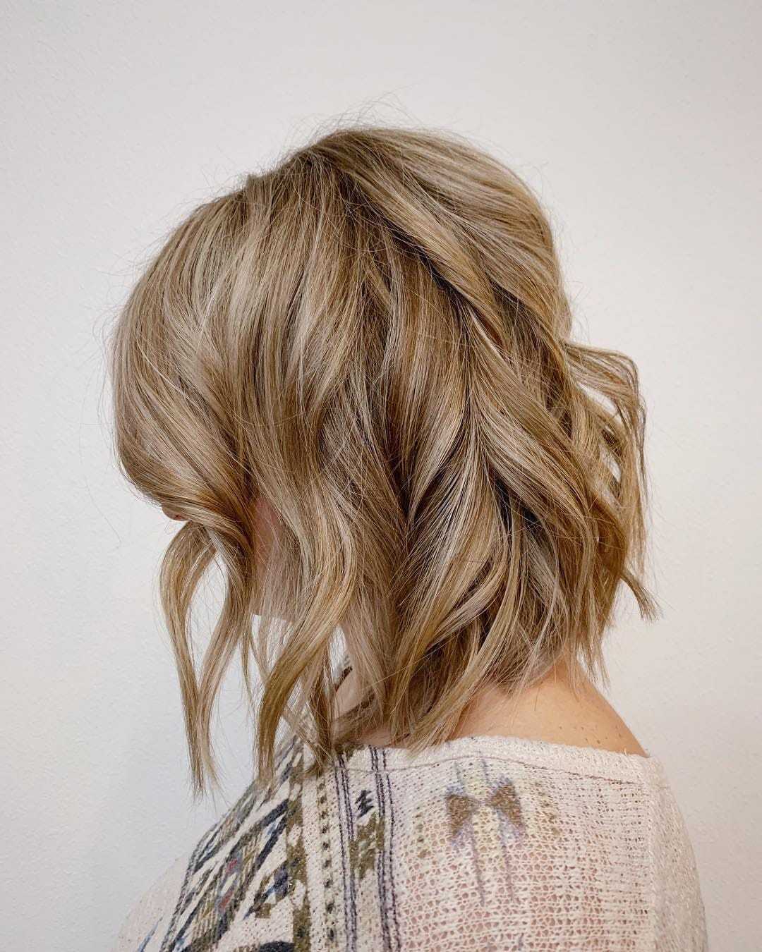 Side view of a person with wavy, shoulder-length blonde hair in a textured bob cut.