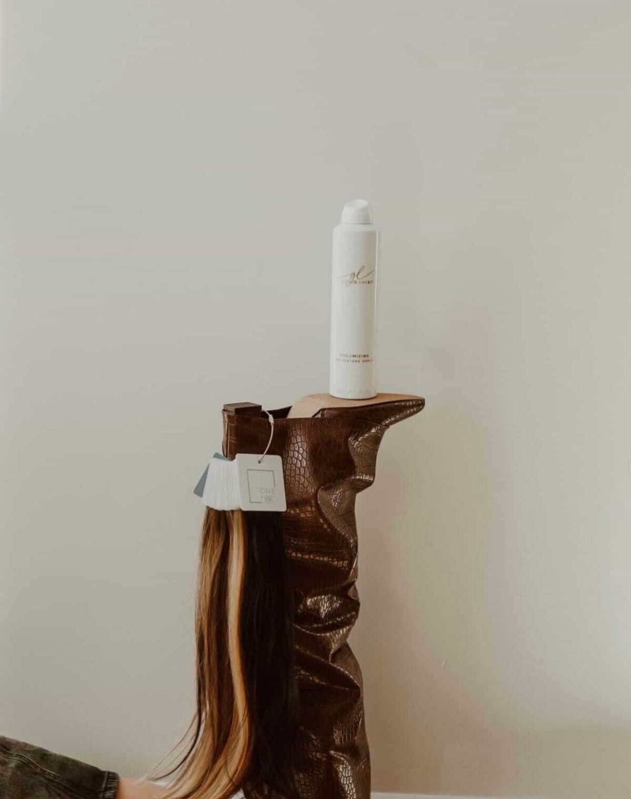 Wine boot holding hair extension and spray bottle on floor.