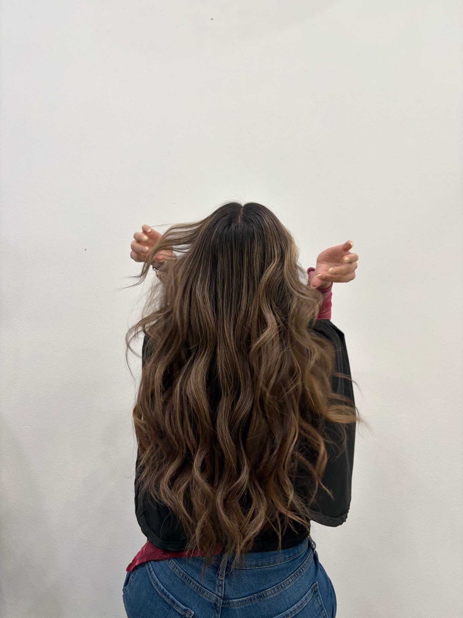 Long, wavy brown hair cascading down a person's back against a plain background.