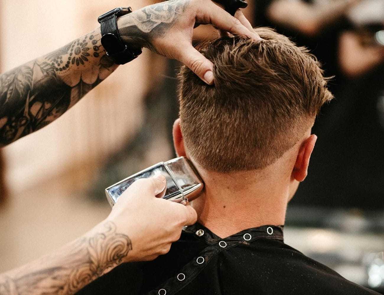 Barber using clippers to shape a man's haircut.