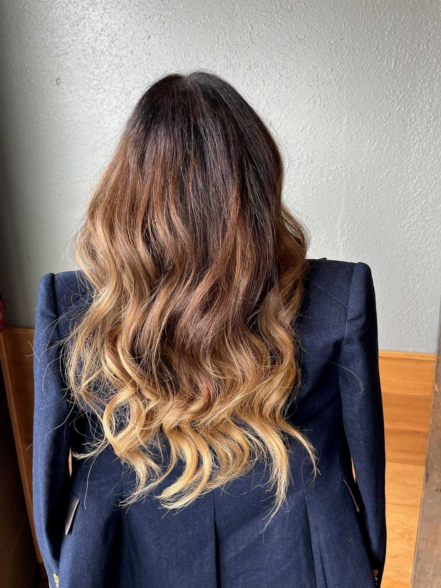 Wavy ombre hairstyle on a person wearing a dark blazer, viewed from the back.